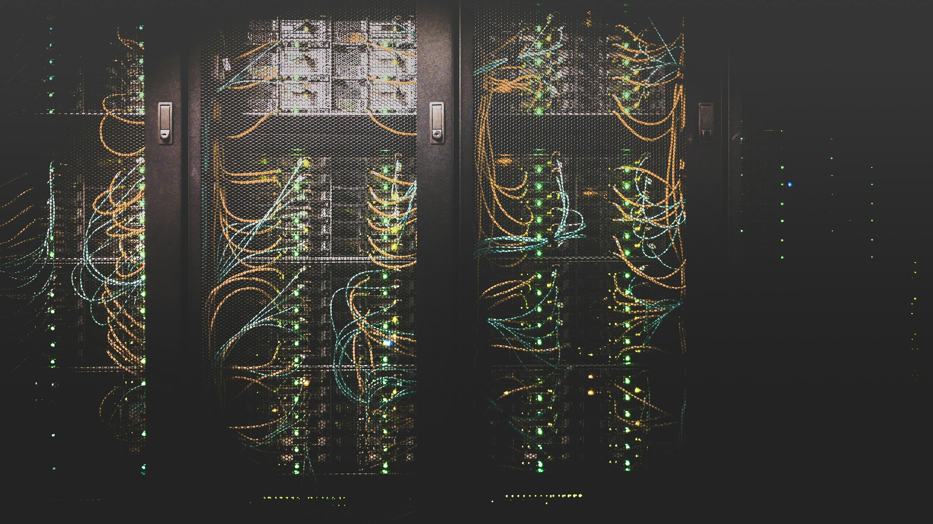Server racks laced with amber and teal patch cabling